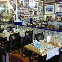 Un restaurante lleno de mesas y sillas y muchos cuadros en las paredes.