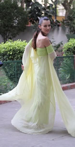 Una mujer con un vestido largo verde camina por la calle.