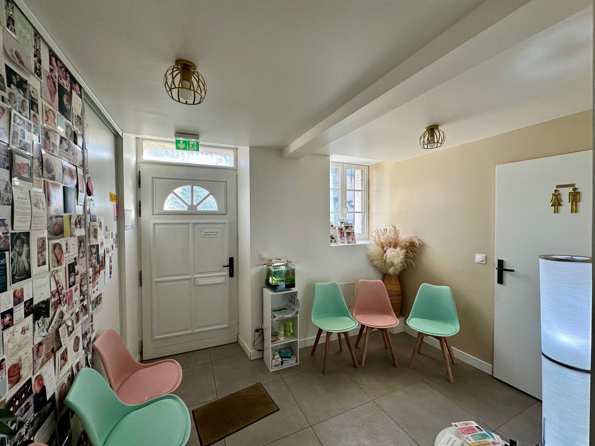 Une femme enceinte vêtue d'un blazer noir est assise en tailleur, les mains posées sur son ventre, dans un portrait de studio en noir et blanc.