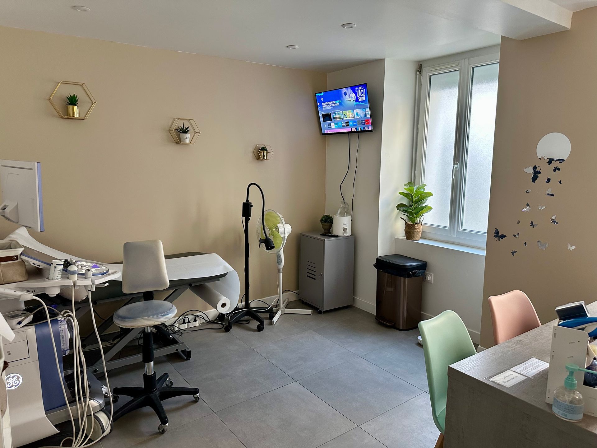 Une femme enceinte vêtue d'un blazer noir est assise en tailleur, les mains posées sur son ventre, dans un portrait de studio en noir et blanc.