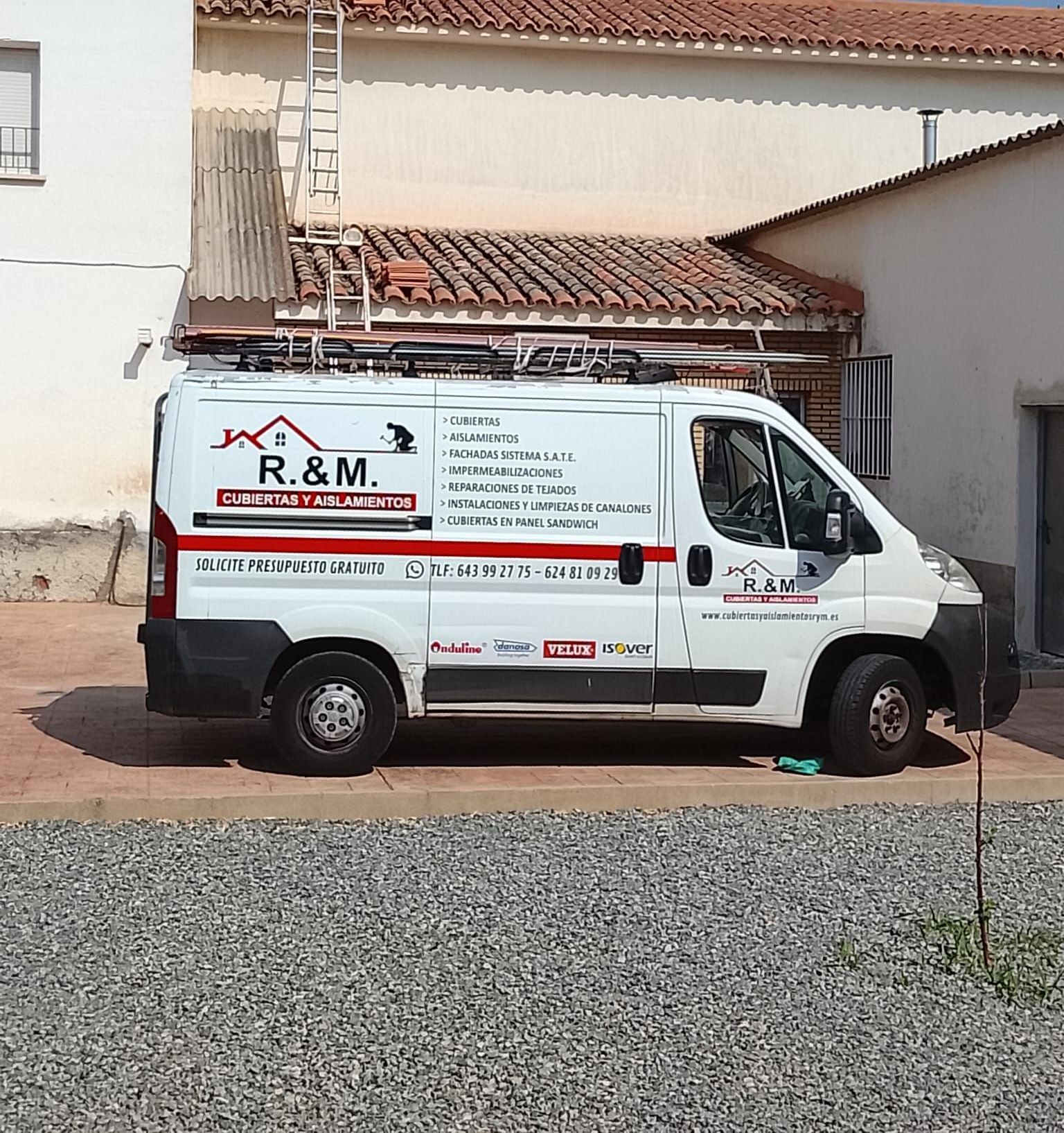 Dos personas en un sitio de construcción, una con chaleco de seguridad y la otra con casco y planos, inspeccionando el edificio sin terminar.