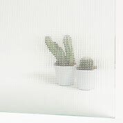 Dos cactus en macetas sobre una superficie blanca, vistos a través de un vidrio texturizado.