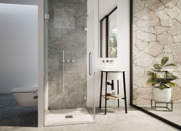 Baño moderno con ducha de cristal, inodoro y lavabo contra una pared texturizada y una planta decorativa.