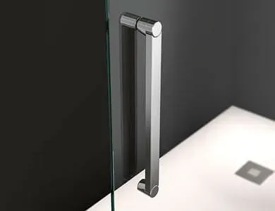 Manija cromada para puerta de ducha sobre panel de vidrio. Fondo gris, base de ducha blanca.