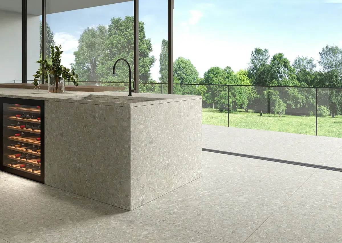 Cocina moderna con isla de piedra y vinoteca, con vistas a un espacio verde exterior.