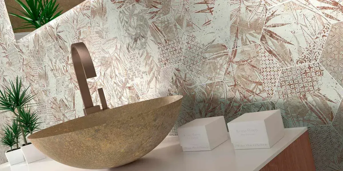 Lavabo con grifo de bronce y pared estampada. Dos pilas de papel blanco sobre la encimera.