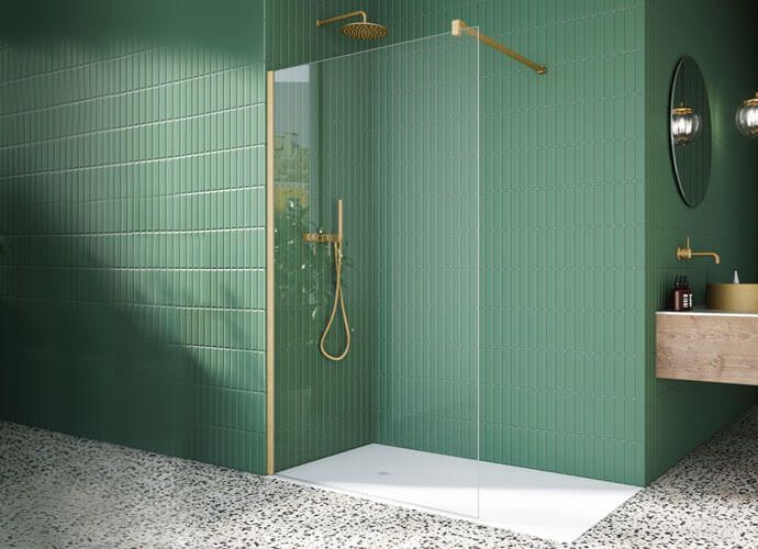 Baño verde con ducha dorada, plato de ducha blanco y azulejos de pared texturizados.