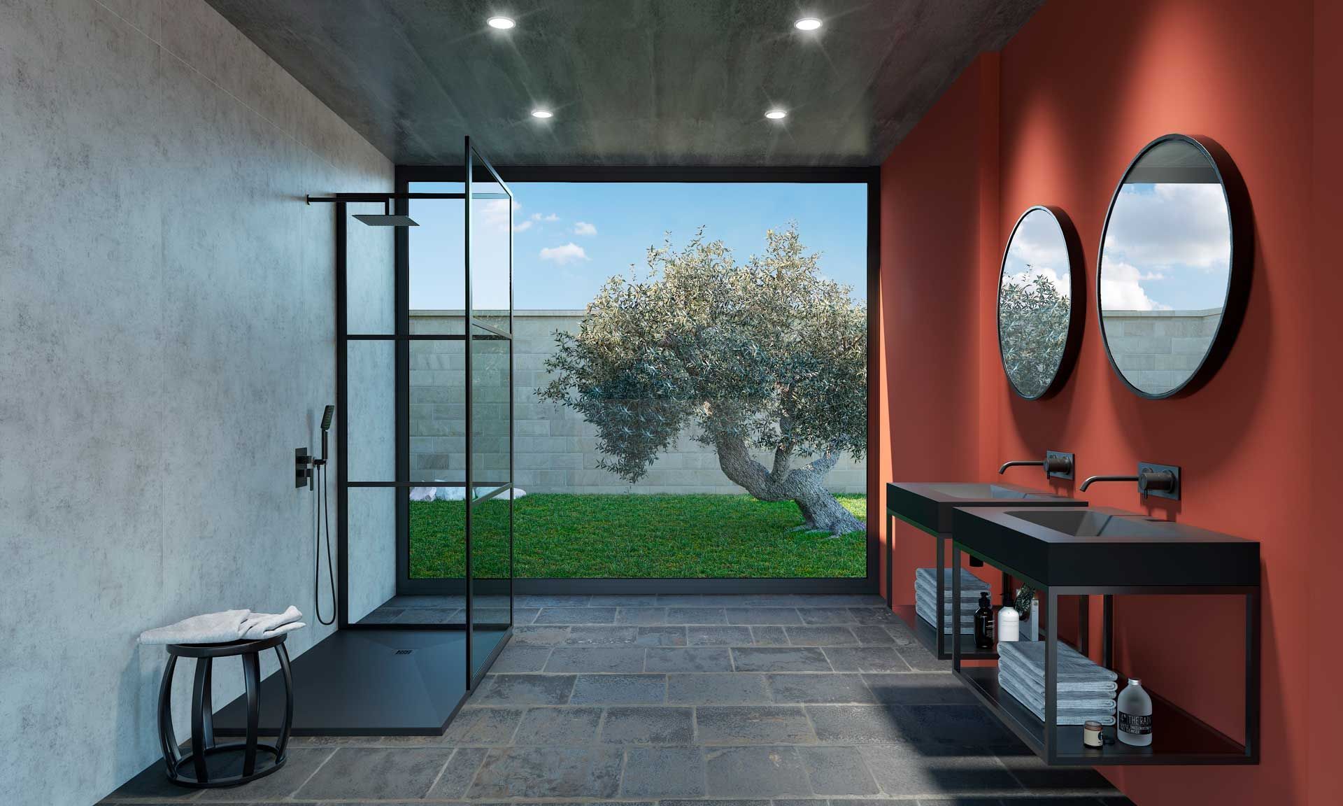 Plato de ducha gris oscuro con desagüe, junto a un panel de vidrio. Azulejos grises y blancos al fondo.