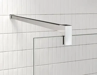 Brazo de ducha cromado que se extiende desde una pared de azulejos blancos, con un cabezal cuadrado a juego.