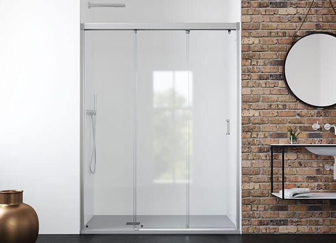 Puerta de ducha corrediza de cristal en un baño moderno con pared de ladrillo y lavabo.