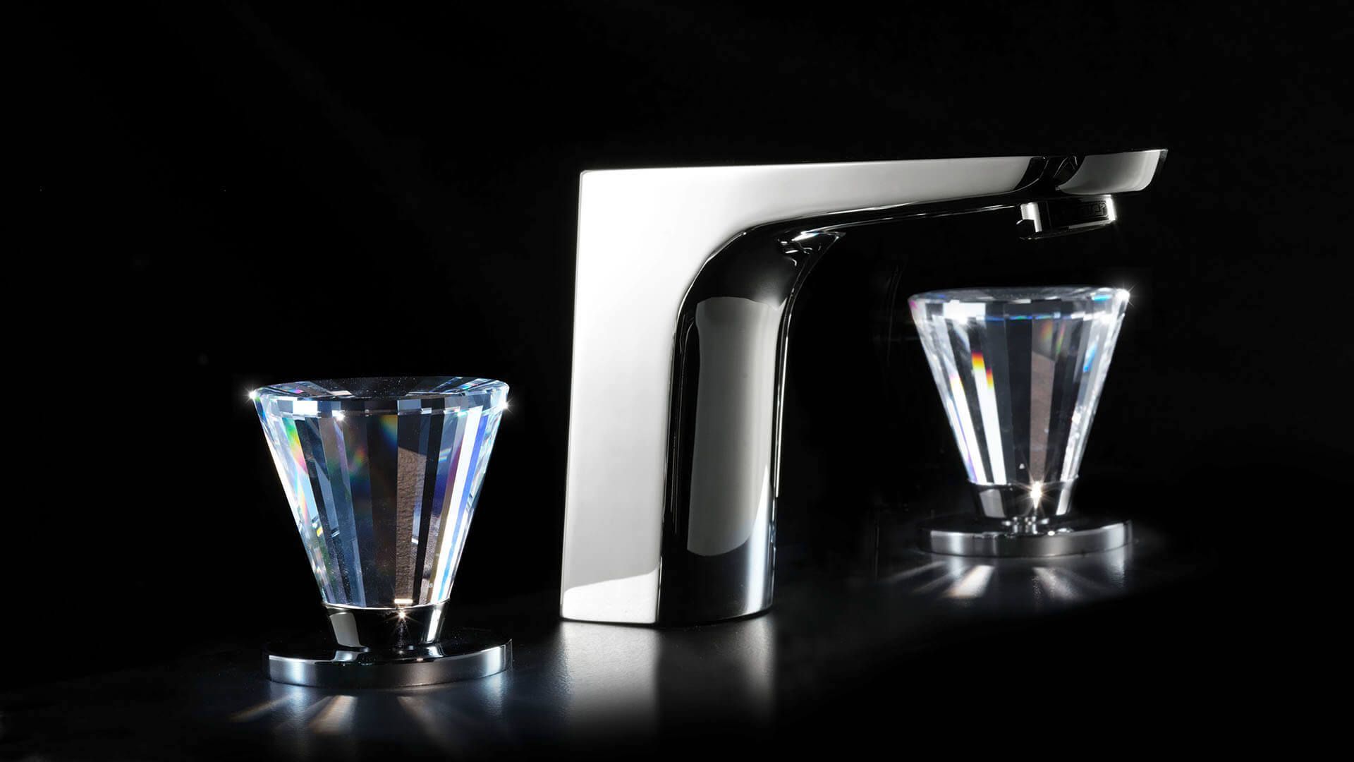 Grifo cromado con manetas de cristal sobre fondo negro.
