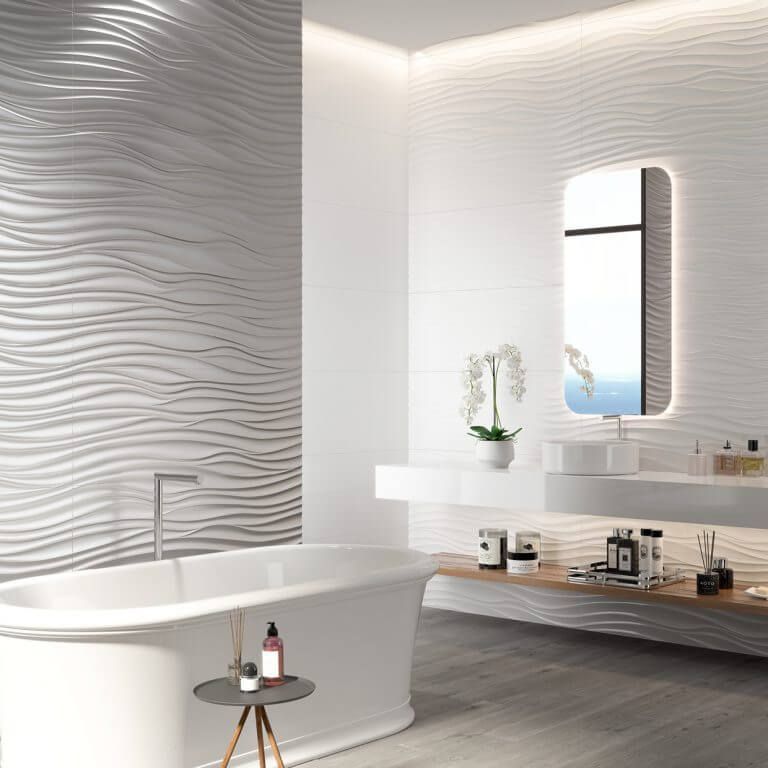 Baño blanco moderno con pared con textura ondulada, bañera y espejo iluminado.