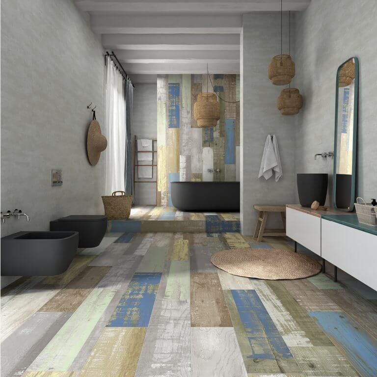 Baño con suelo imitación madera multicolor, bañera negra y pared decorativa revestida con paneles de madera.