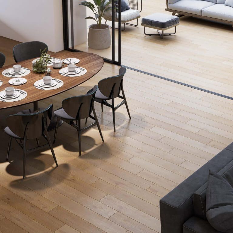 Comedor con mesa de madera, sillas y patio exterior visible a través de puertas de vidrio.