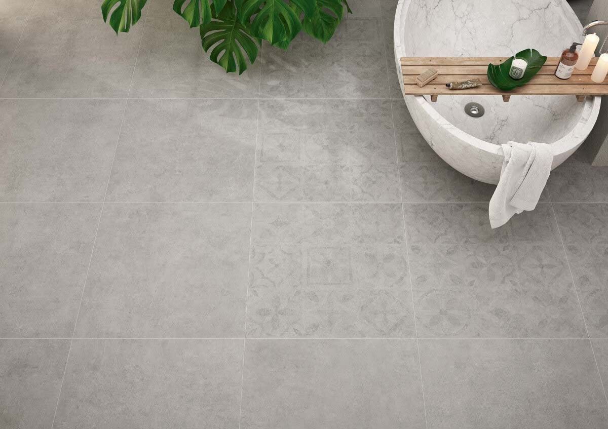Suelo de baño gris con bañera blanca y planta verde.