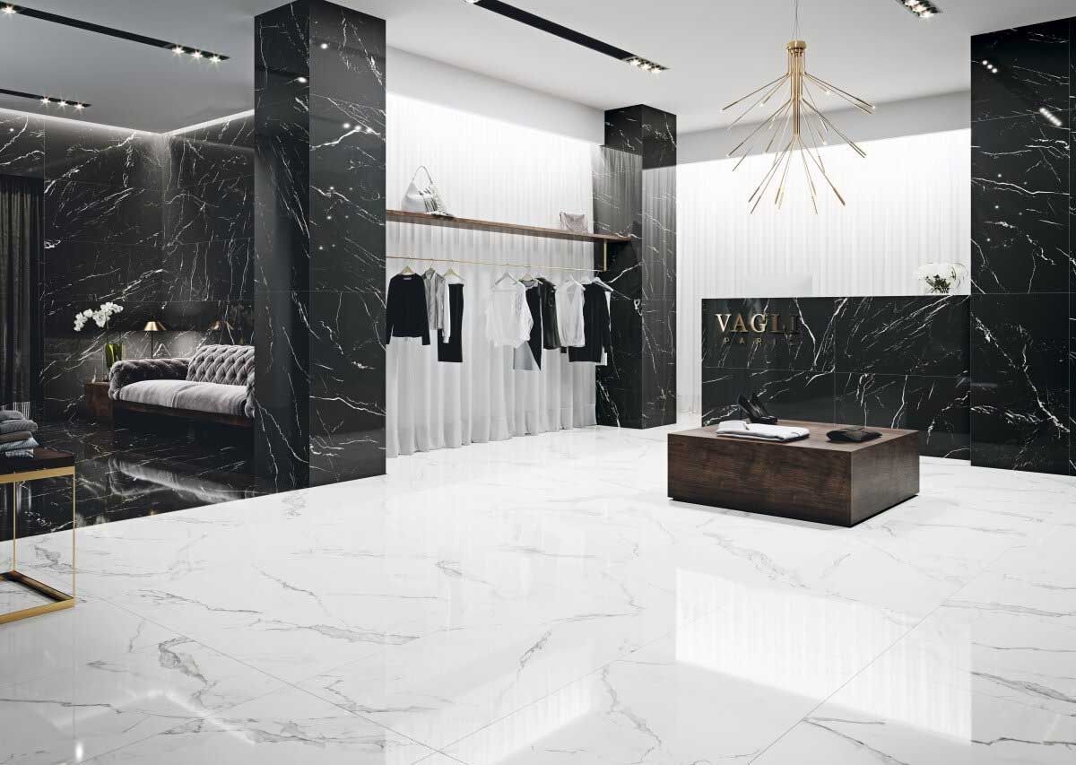 Elegante interior boutique con paredes de mármol negro y pisos de mármol blanco, percheros y mesas de exhibición.