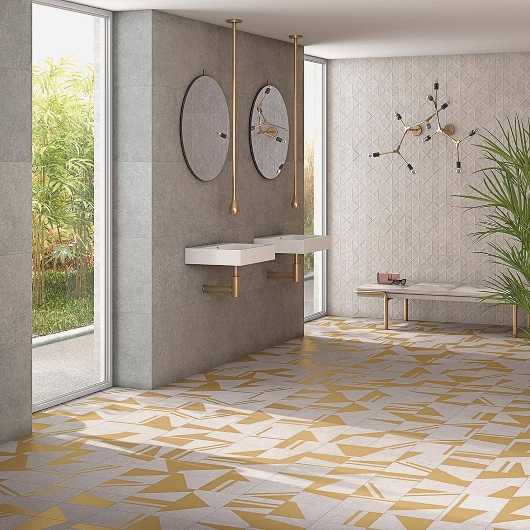 Baño moderno con azulejos geométricos dorados, ventanas grandes y lavabos flotantes.