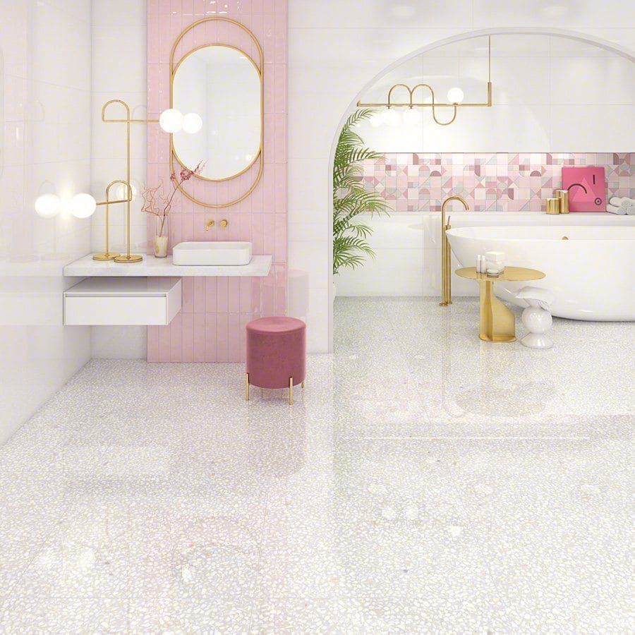 Baño moderno rosa y blanco con suelo de terrazo, detalles dorados y bañera.
