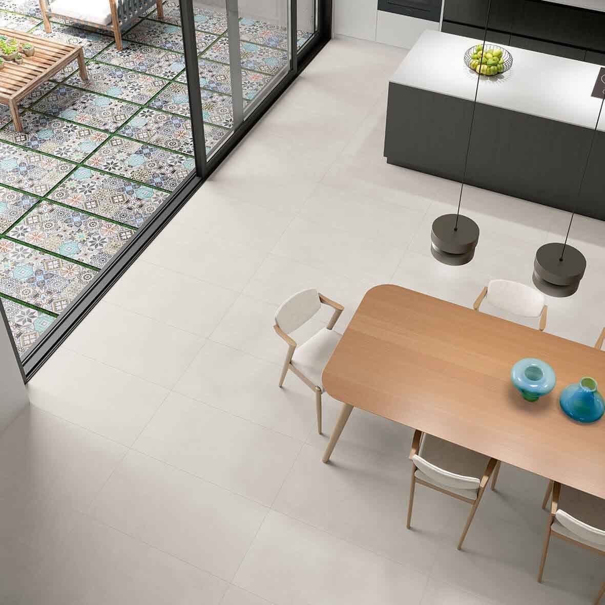 Cocina y comedor modernos con pisos claros, una isla oscura y un patio visible a través de grandes ventanales.