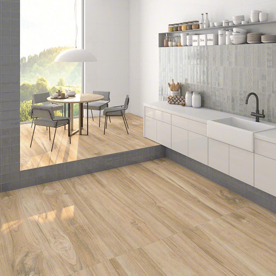 Cocina moderna con suelos imitación madera, armarios blancos y fregadero. El comedor ofrece vistas a un verde paisaje.