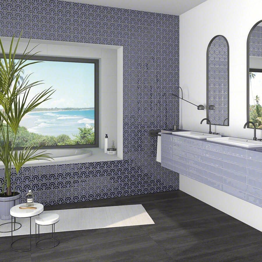 Baño con azulejos estampados en azul, gran ventanal con vista al mar y piso de madera oscura.