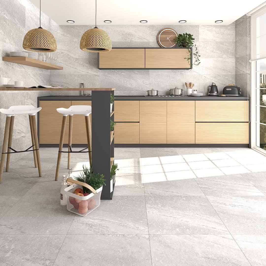 Cocina moderna con gabinetes de madera clara, encimeras grises y revestimiento de pared símil piedra.
