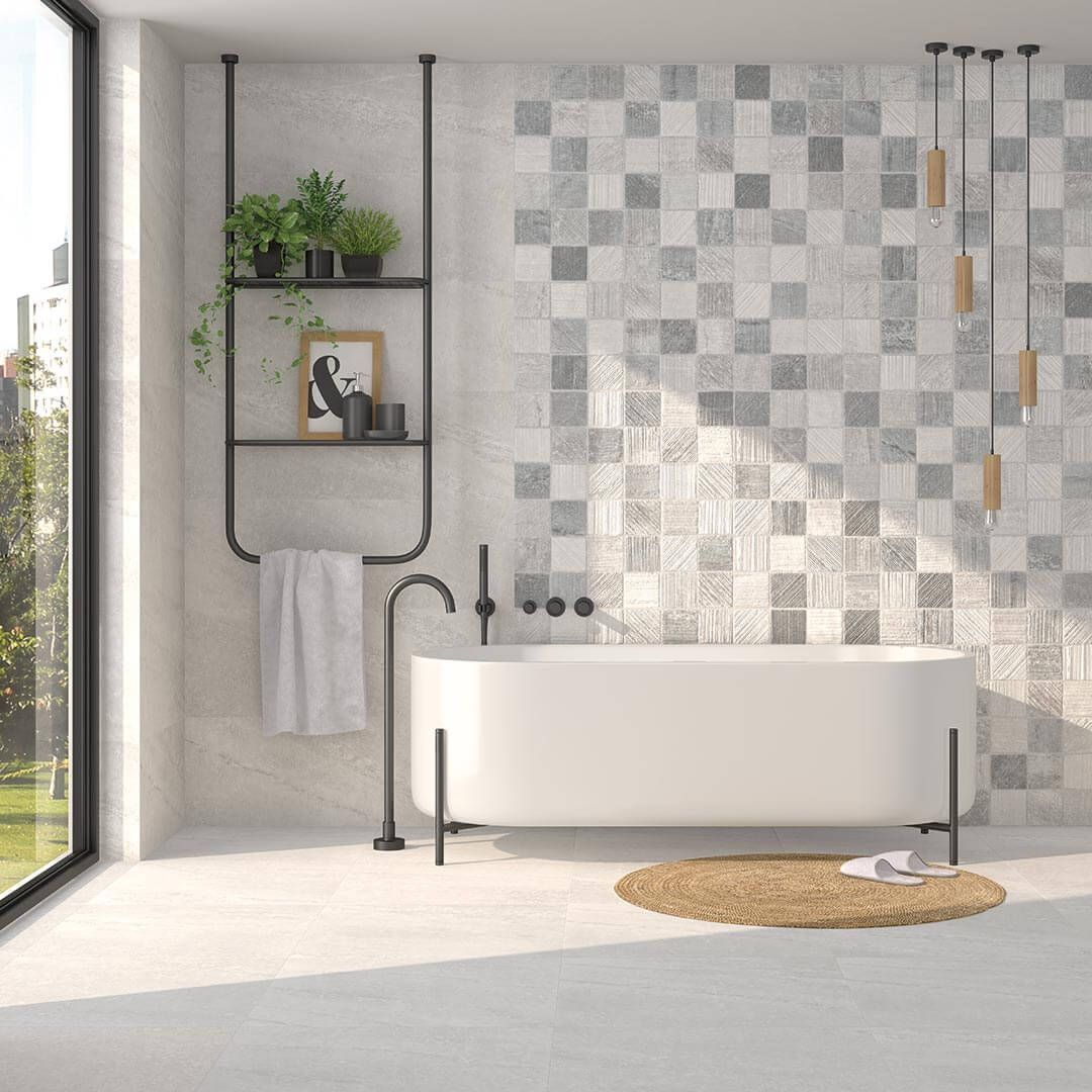 Baño moderno con bañera blanca, pared de azulejos a cuadros, accesorios negros y un estante con plantas.