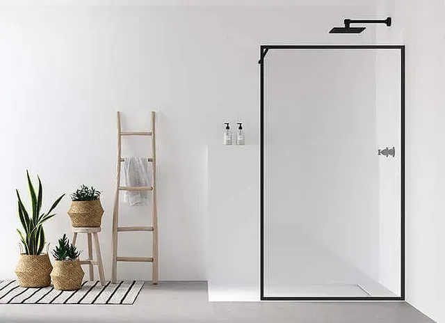 Baño moderno con ducha con marco negro, plantas, escalera de madera y paredes y suelo blancos.