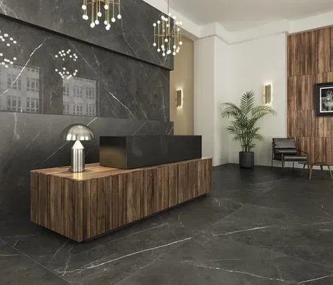 Elegante vestíbulo con paredes de mármol negro y mostrador de recepción de madera oscura.