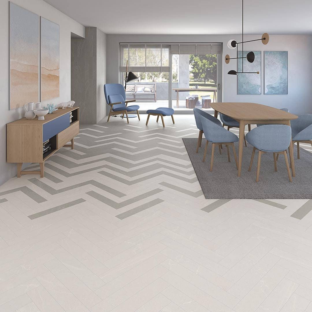 Sala de estar con pisos de madera clara, diseño de chevron y detalles en azul.