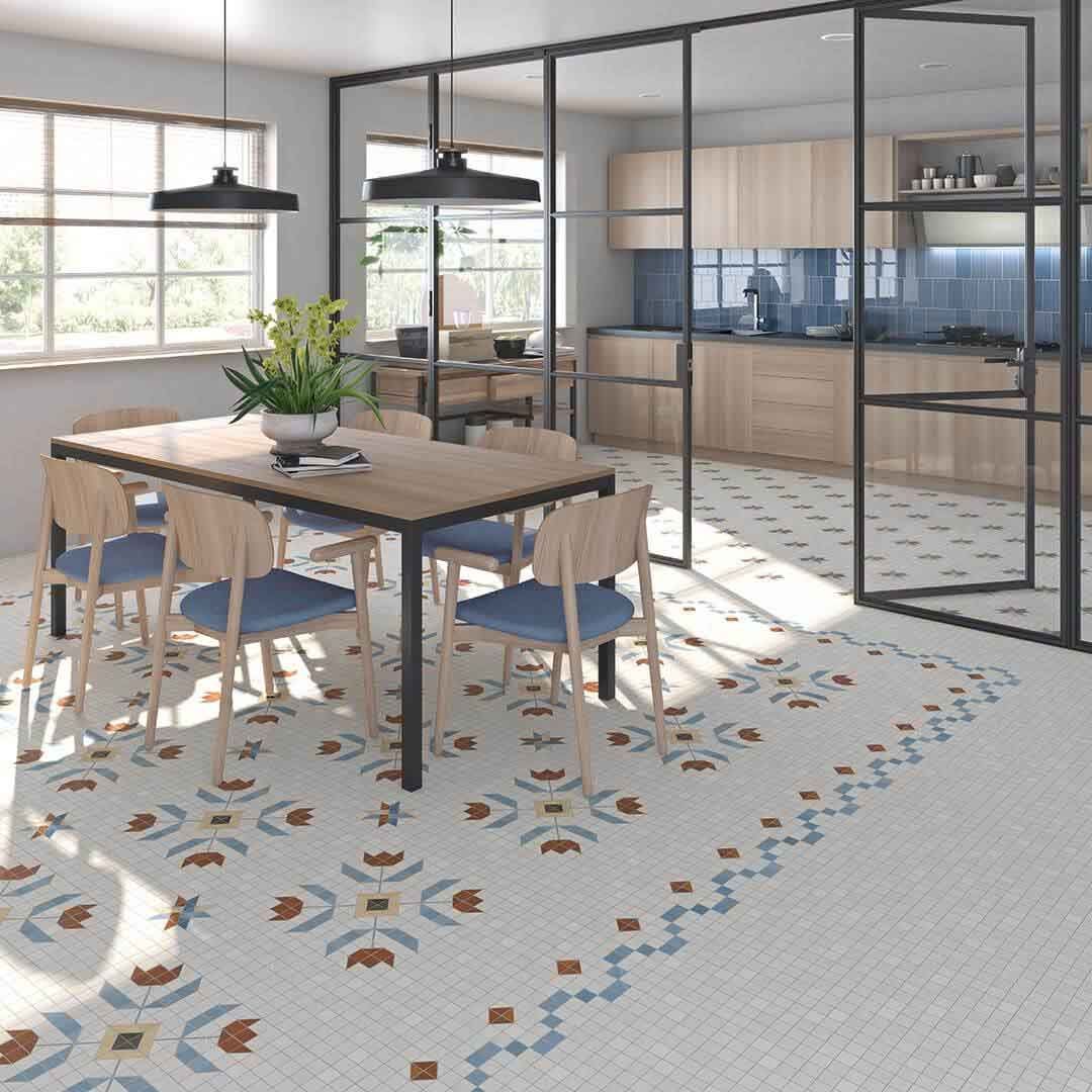 Cocina con mesa de comedor, sillas azules, piso estampado, gabinetes con paredes de vidrio, gabinetes de madera clara e iluminación negra.