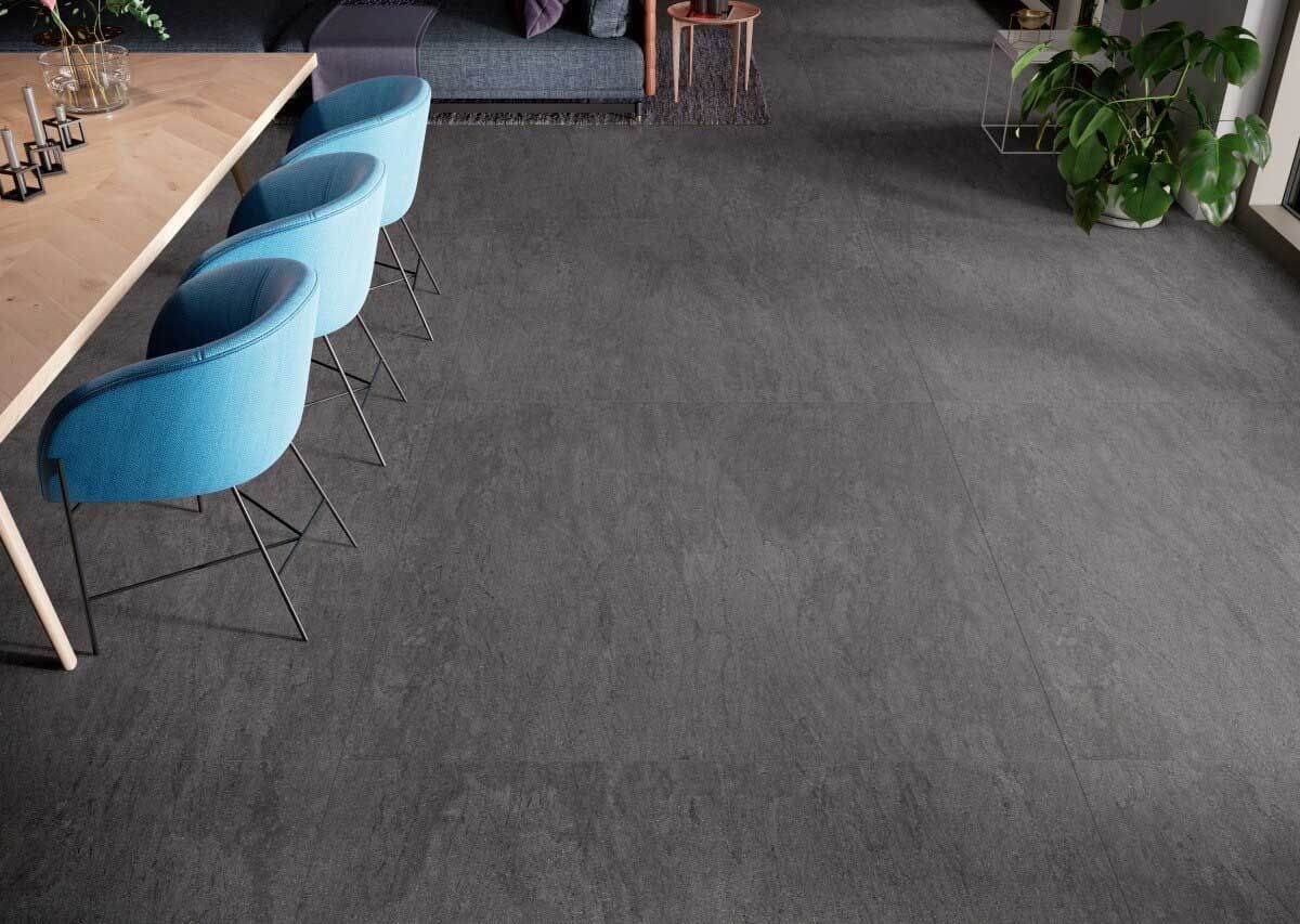 Comedor con mesa de madera, sillas azules y suelo gris oscuro.