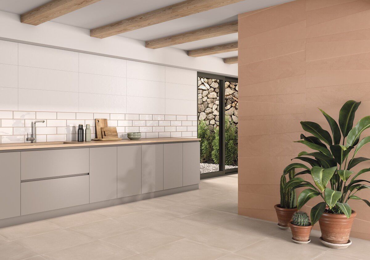 Cocina moderna con tonos neutros: salpicadero blanco, gabinetes grises, piso y paredes beige, plantas.