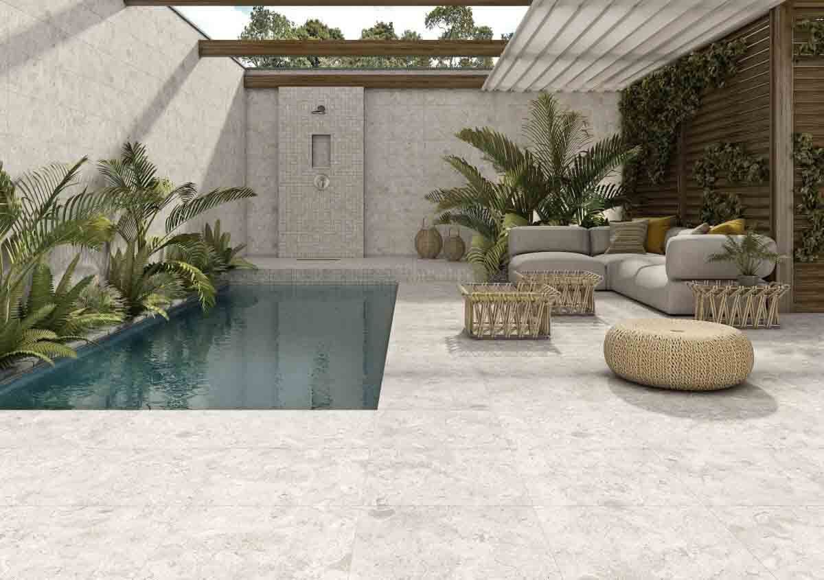 Patio al aire libre con piscina, zona de estar con sofá y exuberante vegetación.