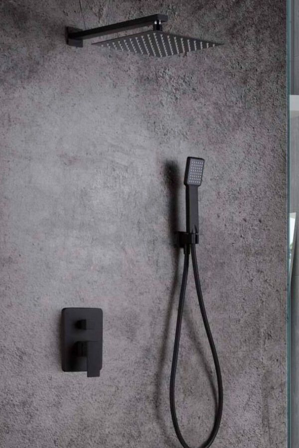 Juego de ducha de color negro sobre una pared gris texturizada; cabezal de ducha cuadrado, rociador de mano y panel de control.