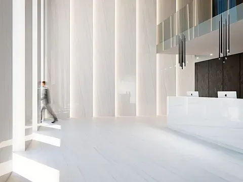 Vestíbulo blanco moderno con una persona caminando frente a un mostrador de recepción.