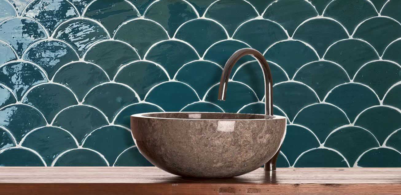 Salpicadero de azulejos con escamas de pescado color verde azulado con lavabo de piedra y grifo curvo.