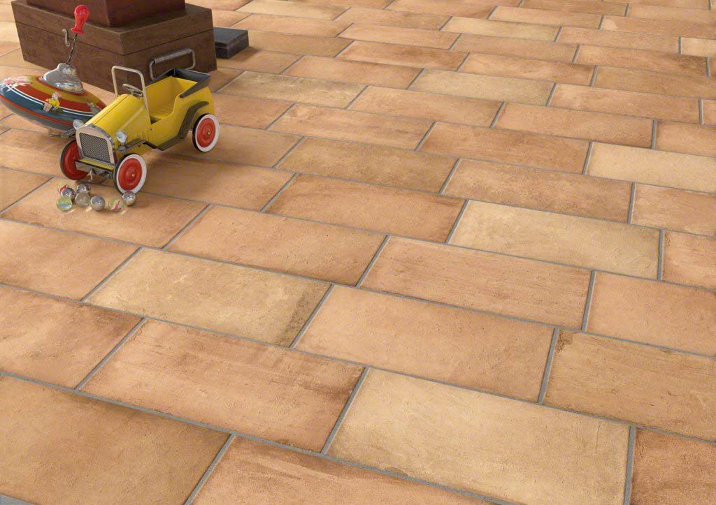 Coche de juguete y barco sobre un suelo de baldosas cerca de una caja de madera, con un coche amarillo.