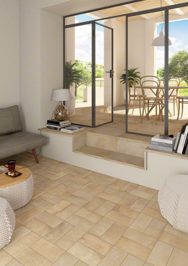 Acogedor espacio de estar con piso de baldosas beige, puertas de vidrio abiertas al comedor al aire libre y muebles neutros.