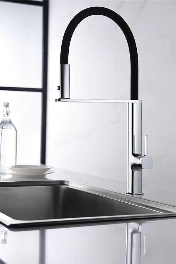 Grifo de cocina cromado con manguera flexible negra sobre un fregadero de acero inoxidable.