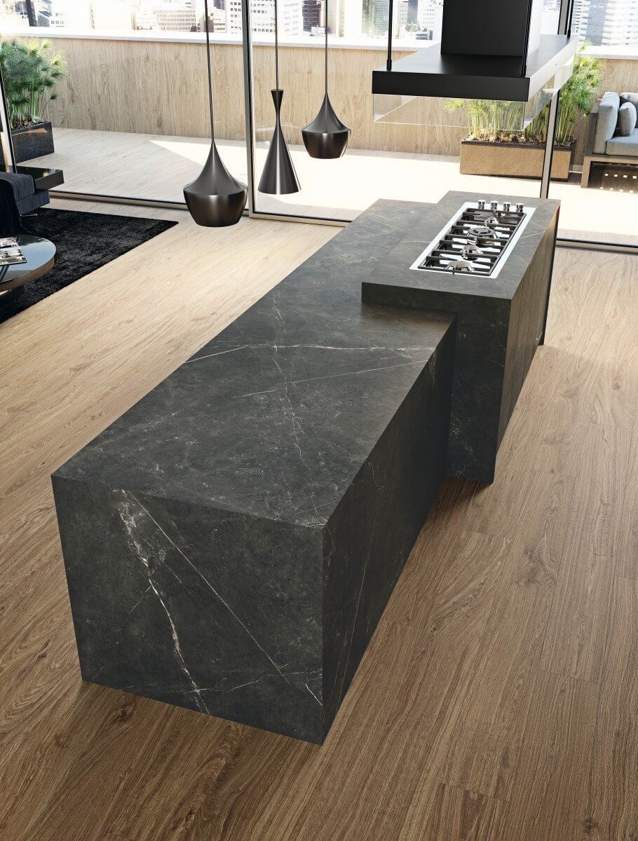 Chimenea de piedra negra en una sala de estar moderna con luces colgantes y pisos de madera.