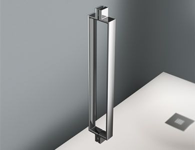 Manija cromada para puerta de ducha con base blanca, contra una pared gris. Diseño rectangular.