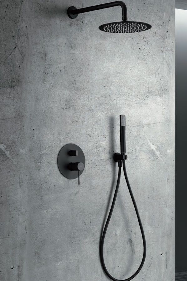 Cabezal de ducha y grifo de color negro sobre una pared de hormigón gris.