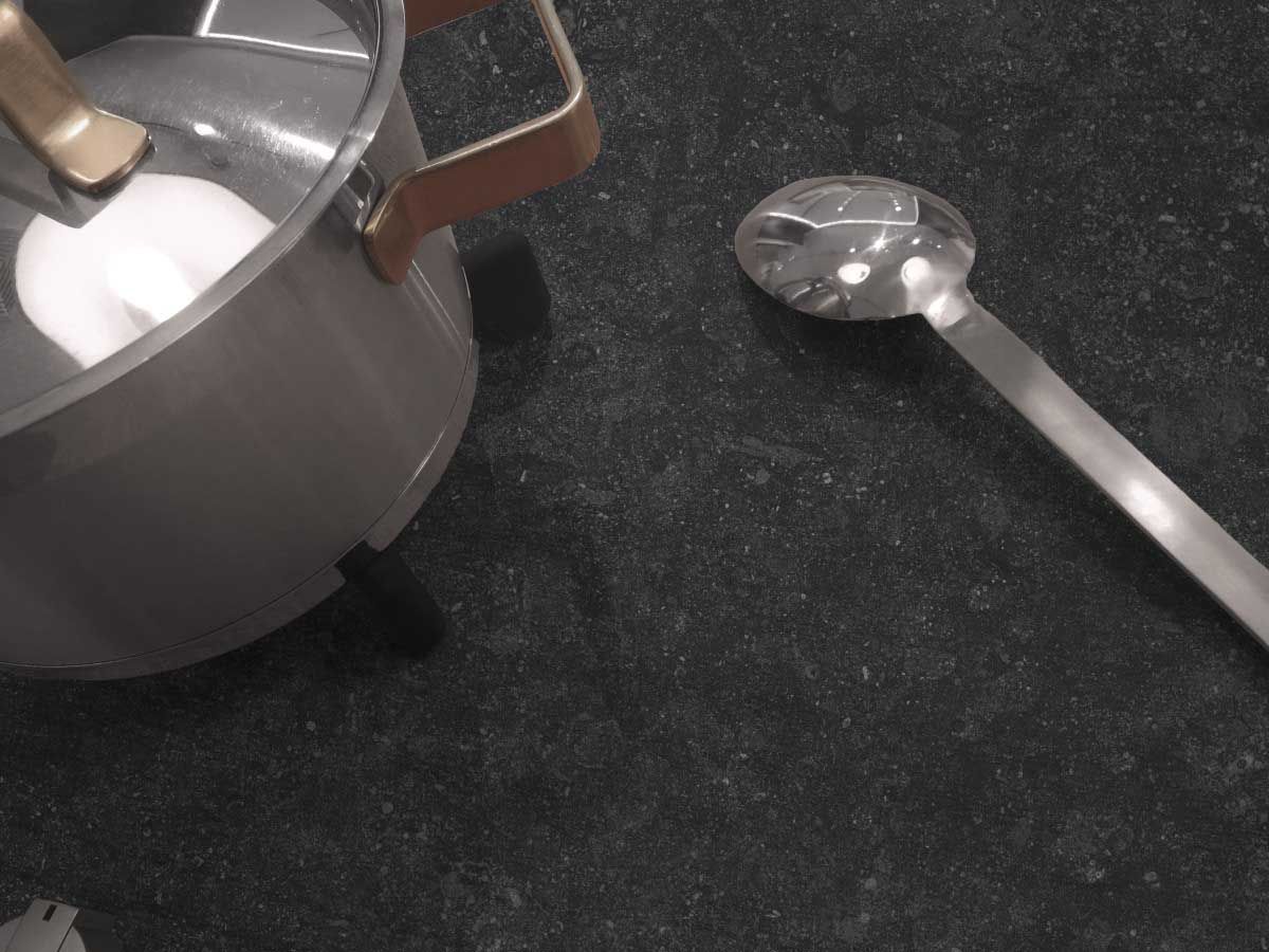 Olla con cucharón sobre una encimera oscura.