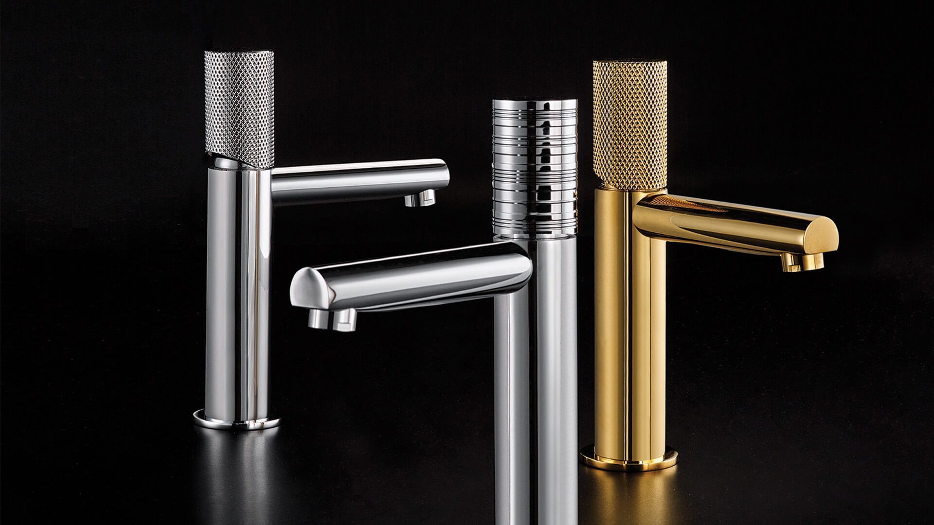 Tres grifos de baño modernos cromados y dorados sobre fondo negro.