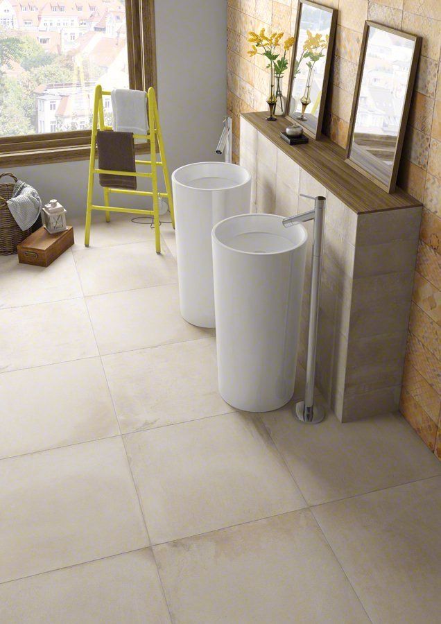 Baño con lavabos de pedestal, pisos de baldosas de color claro y un toallero amarillo.