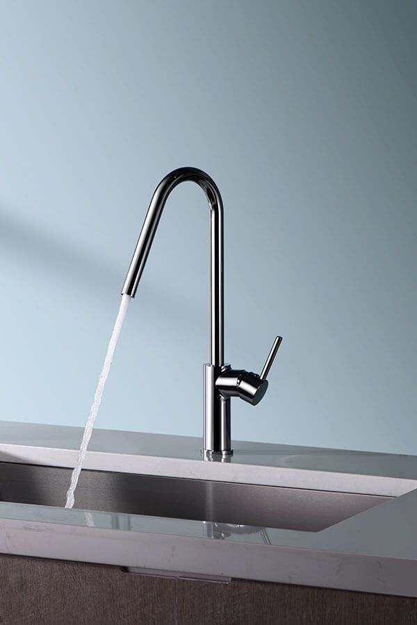 Grifo de cocina cromado con agua que fluye hacia un fregadero sobre un fondo azul claro.