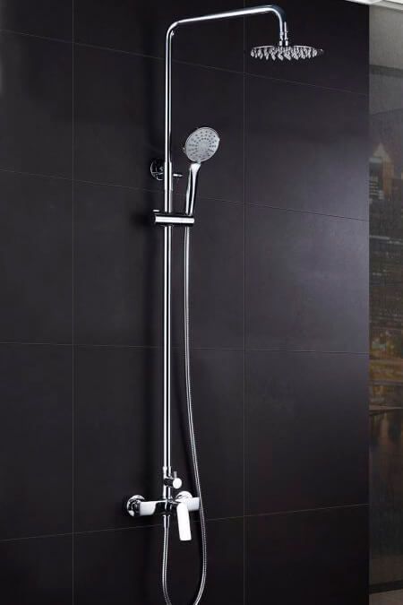 Sistema de ducha cromado con cabezales de ducha de mano y de techo sobre azulejos negros.