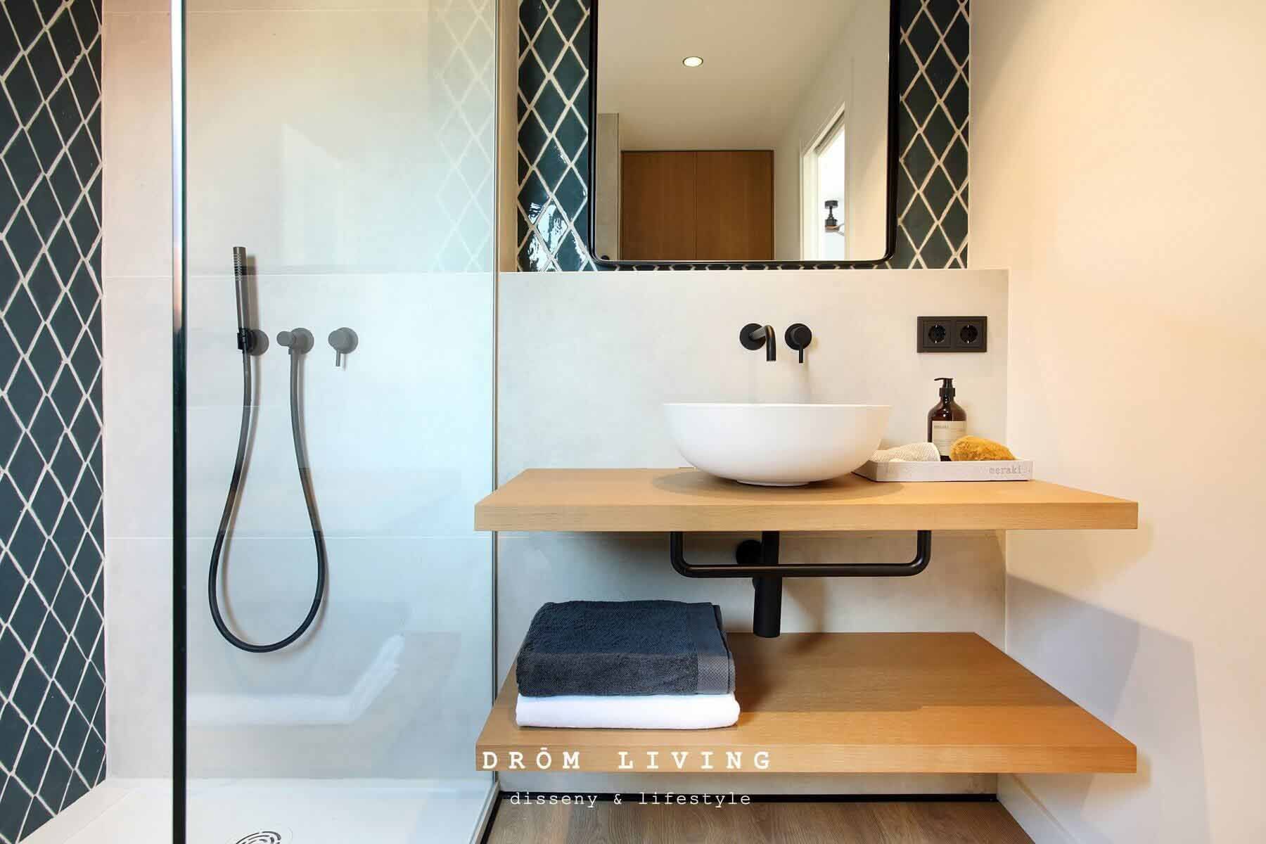 Baño moderno con tocador de madera y ducha a ras de suelo.