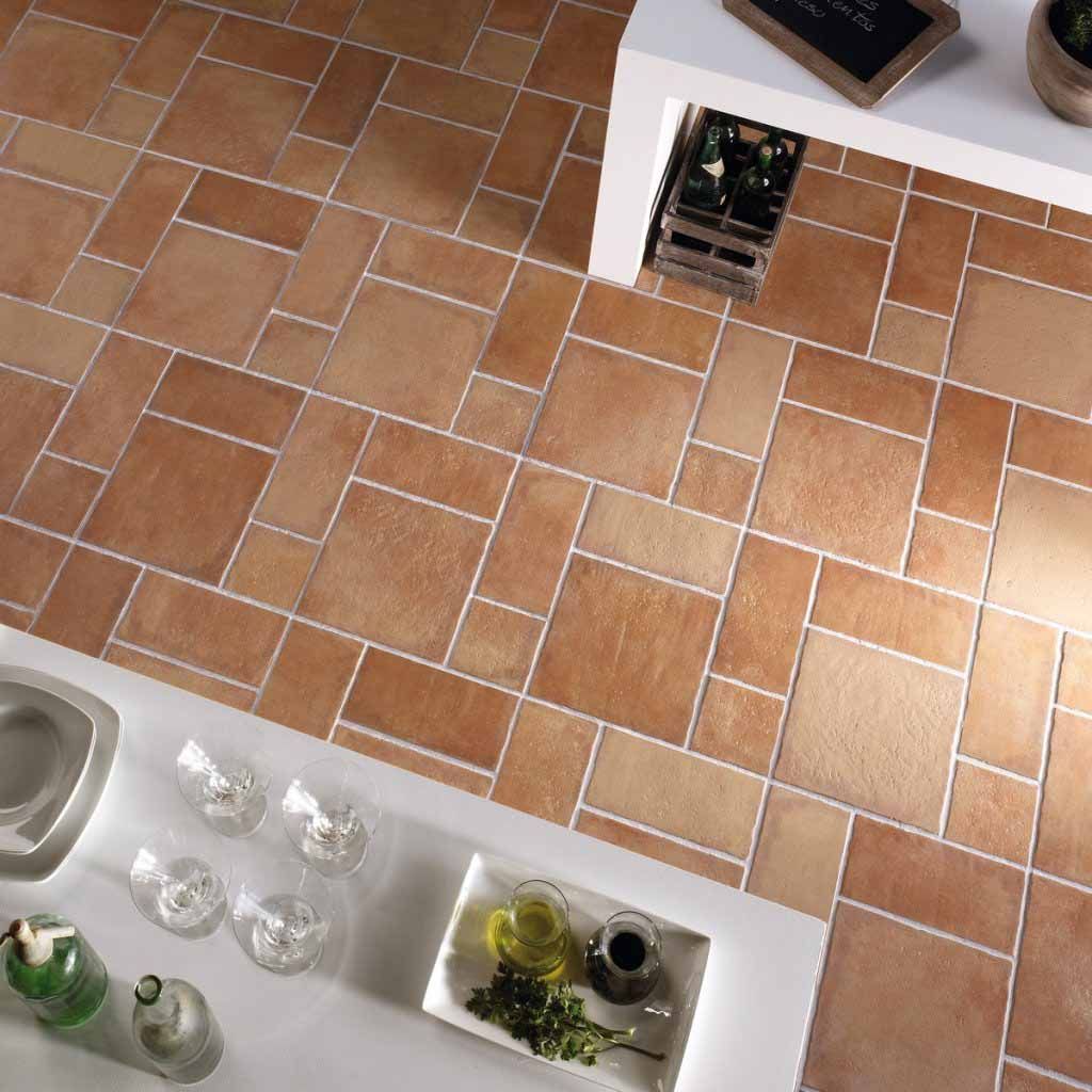 Suelo de baldosas marrones con lechada blanca. Encimera de cocina con cristalería y comida.